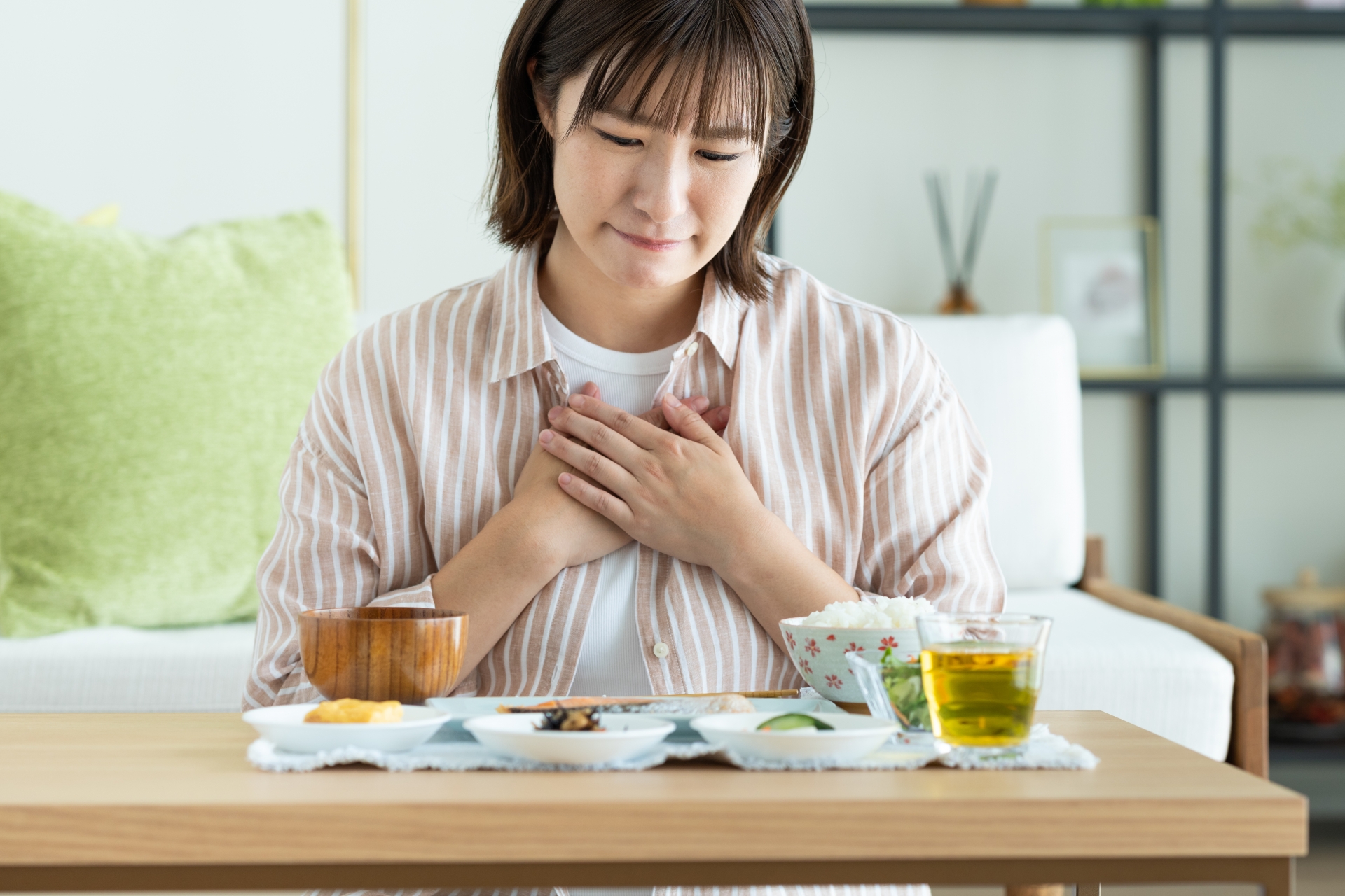 食事を前に胸を押さえる女性