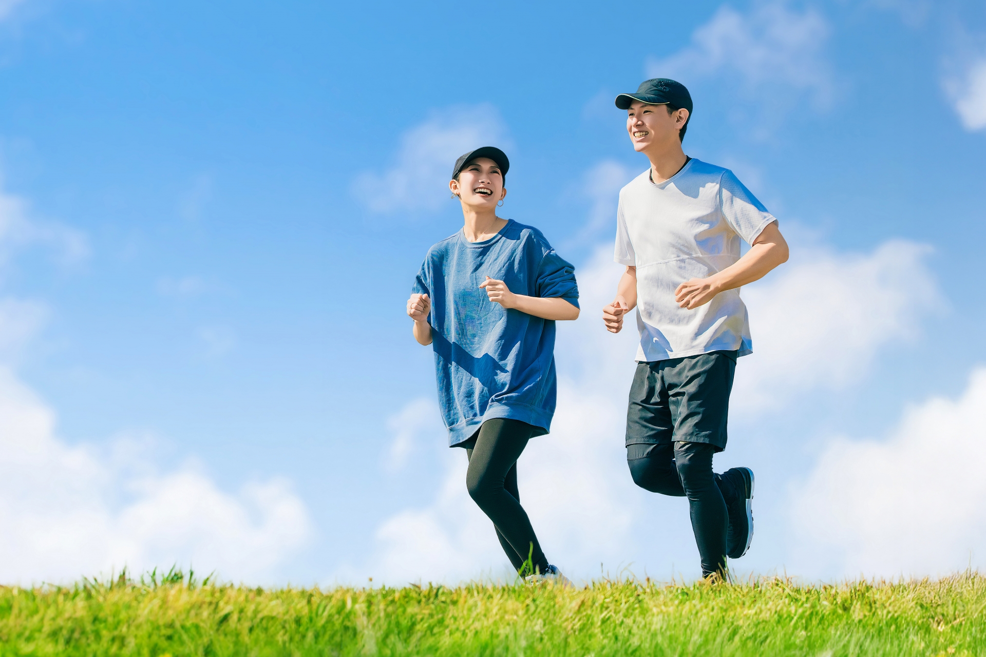 青空の下でジョギングを行う男女