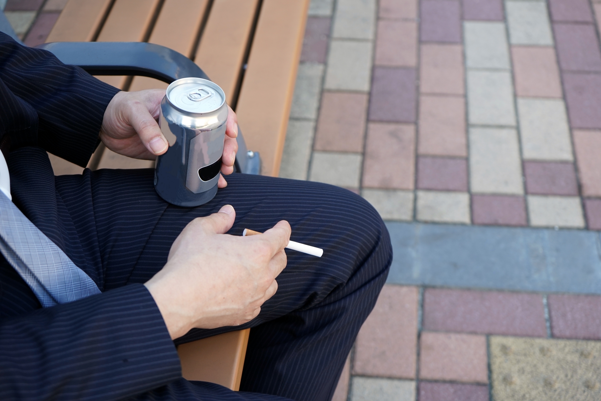 ベンチに座り飲酒・喫煙する男性