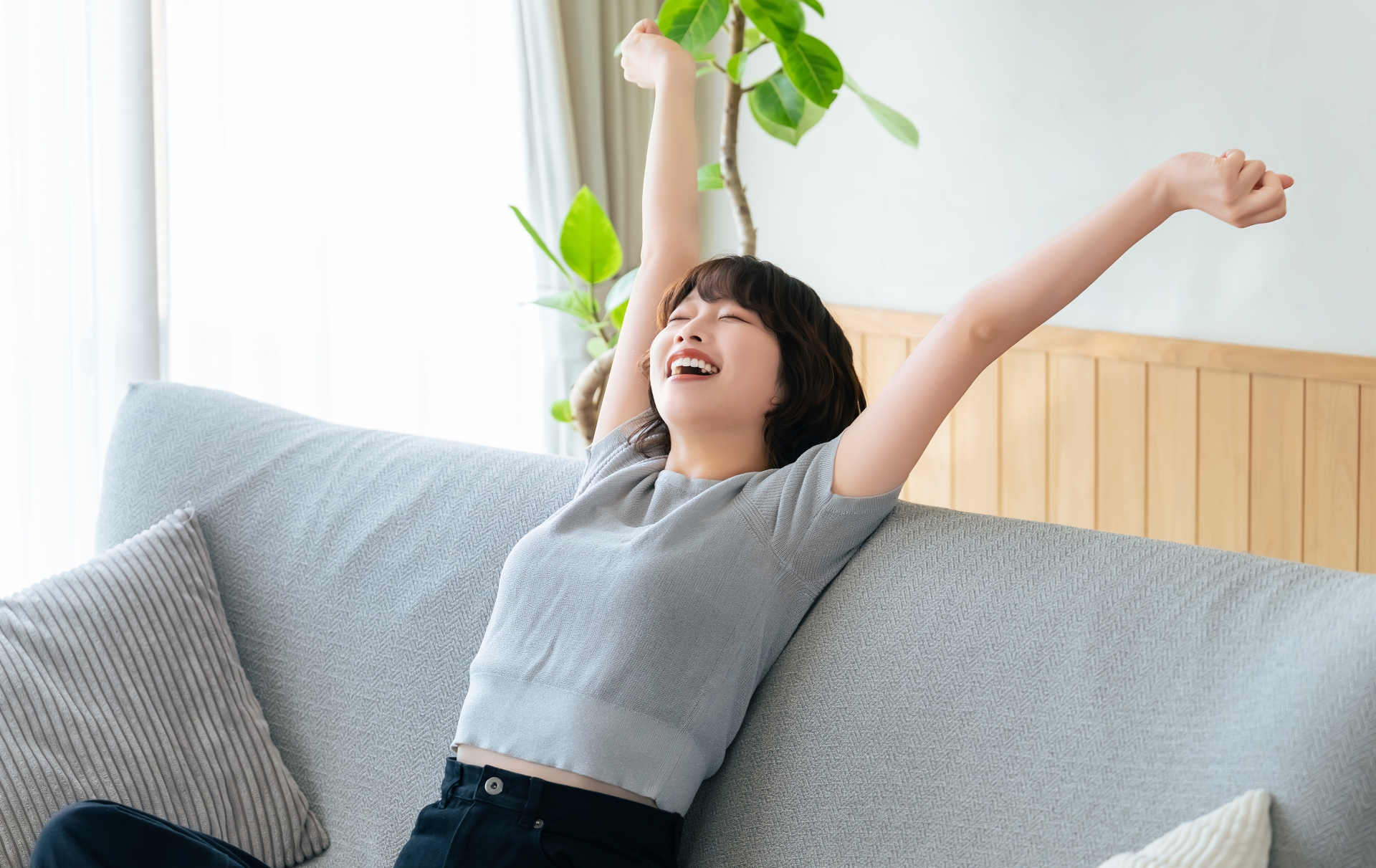 ソファに座り腕を伸ばす女性