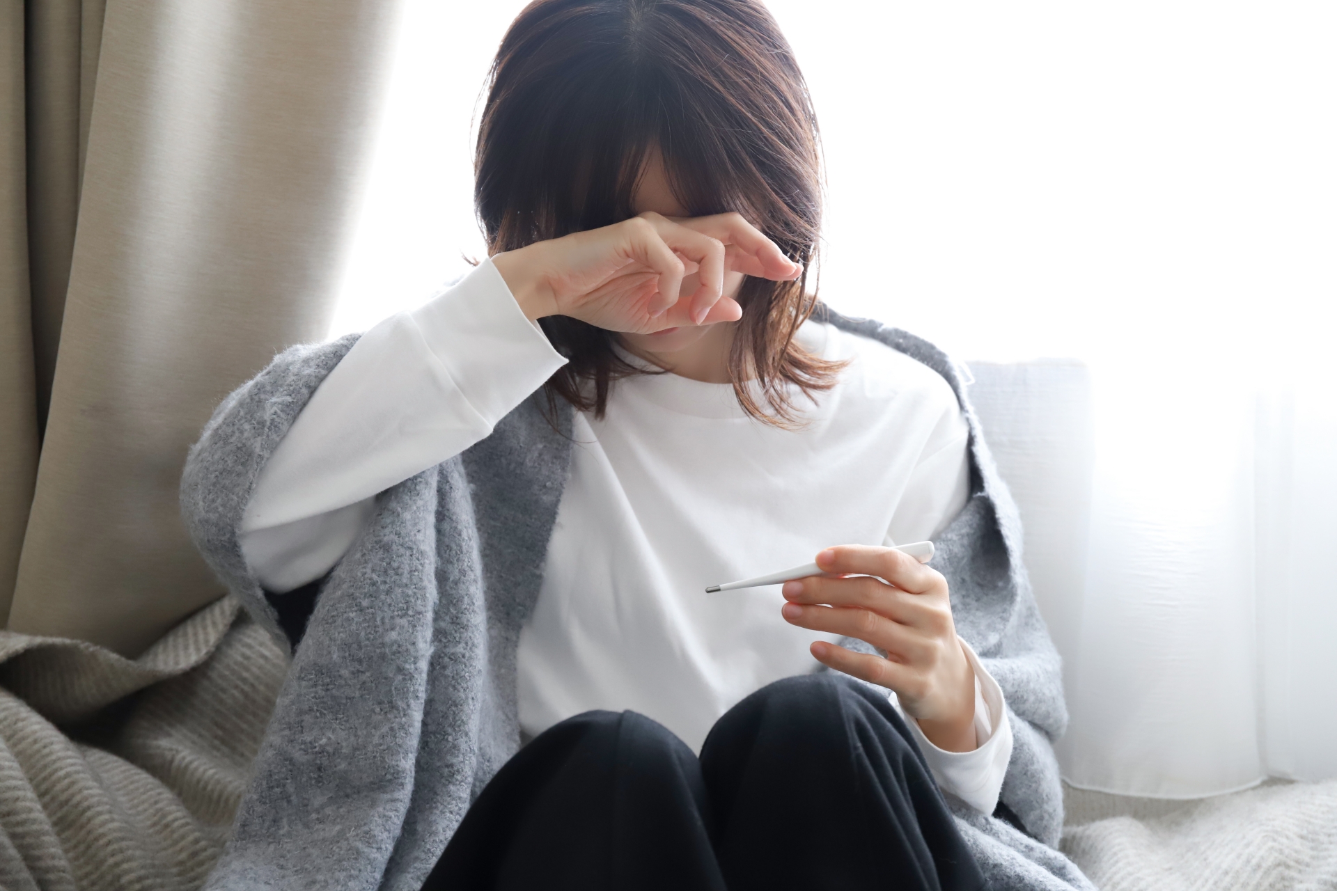 体温計を見る体調不良の女性