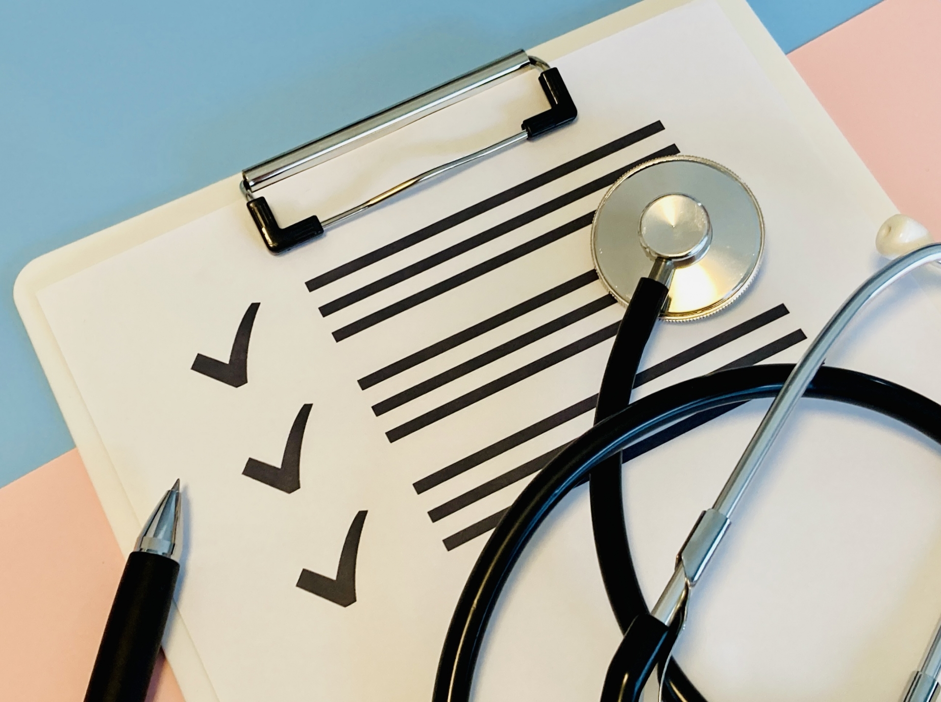 チェックリストの用紙の上にペンと聴診器が置かれている