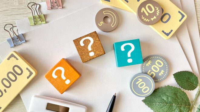 机の上にお金を模したブロックと？が書かれたブロックが置かれている様子