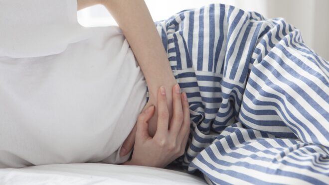 腹部を押さえて横になる女性