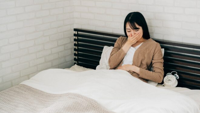 ベッドで吐き気を感じている女性
