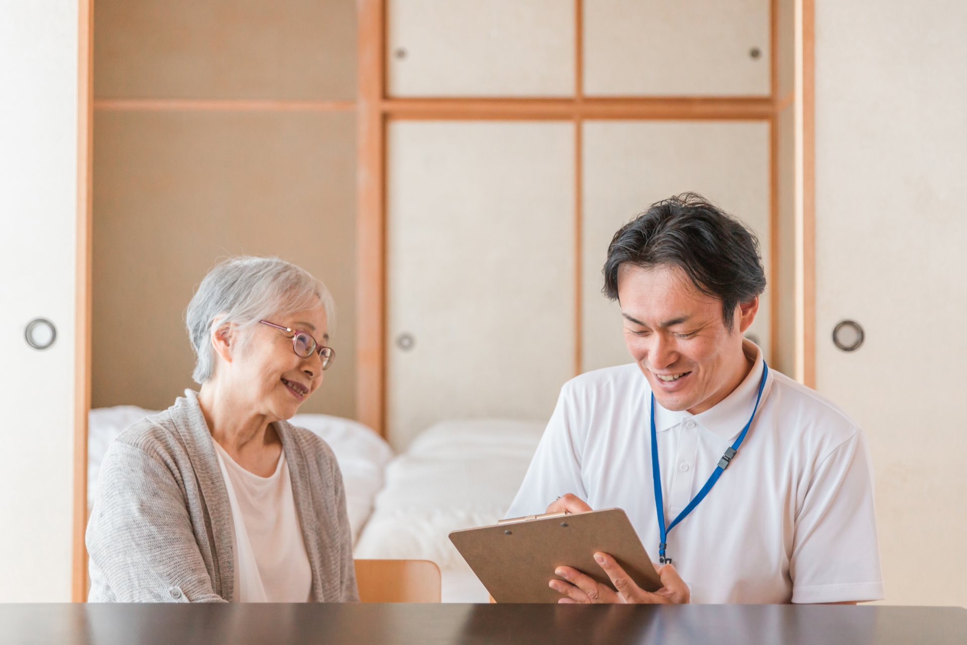 高齢女性と介護士が笑顔で談笑している様子