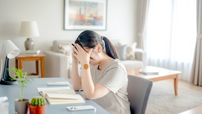 倦怠感のため頭を押さえる女性