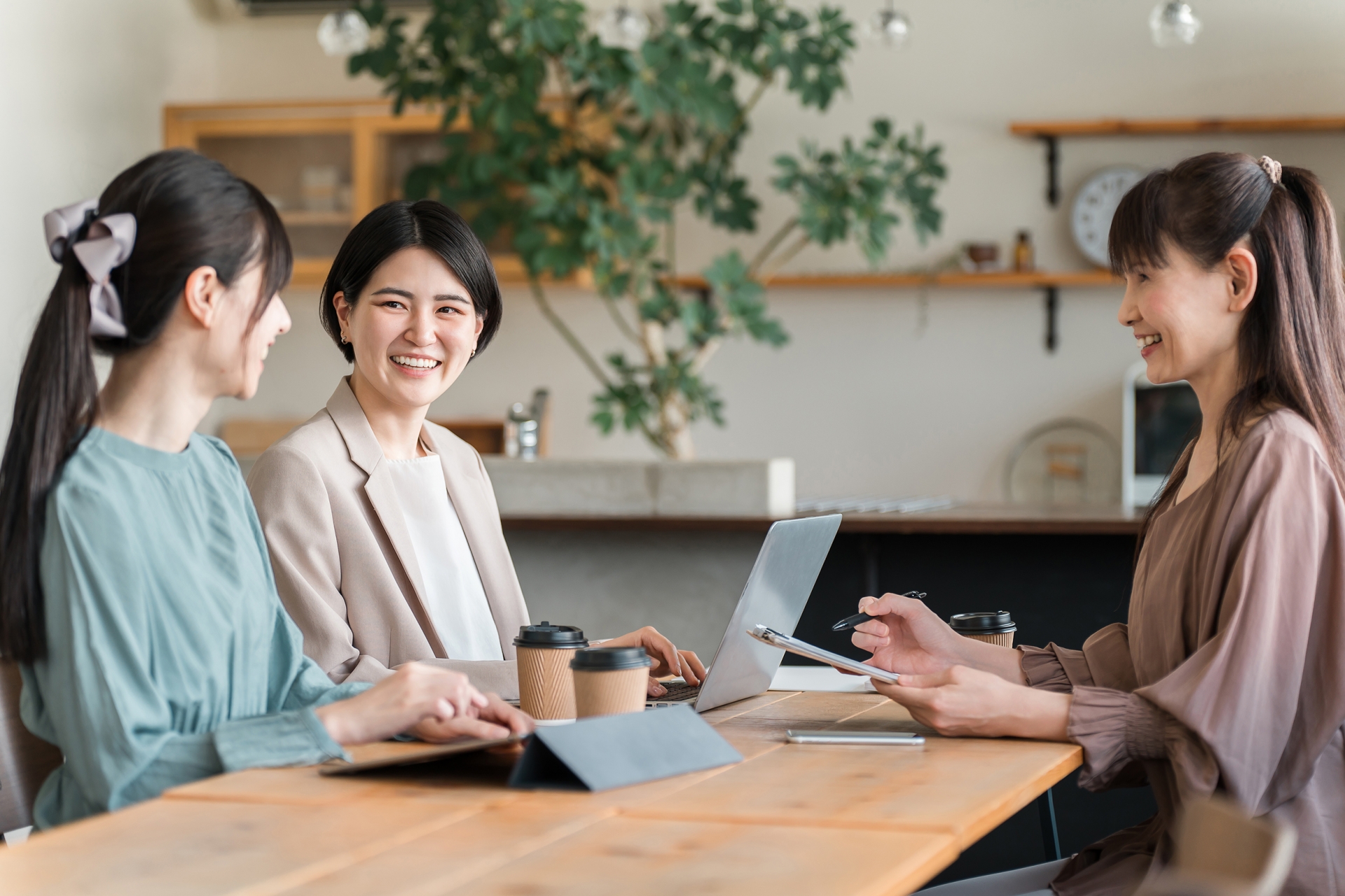 ノートパソコン・タブレットを拓きながら談笑する3人の女性