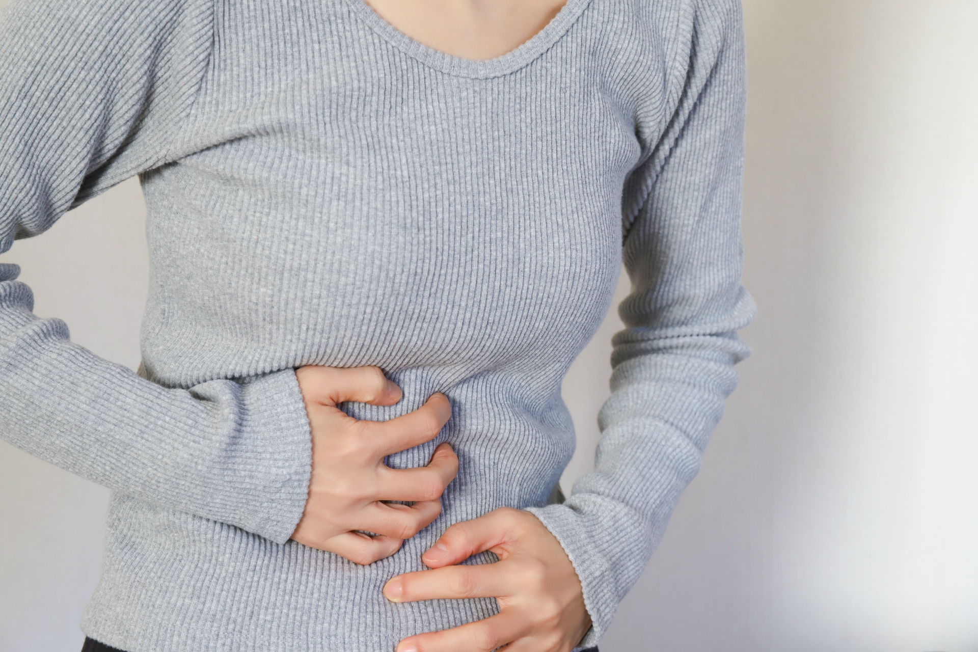 胃のあたりを押さえる女性