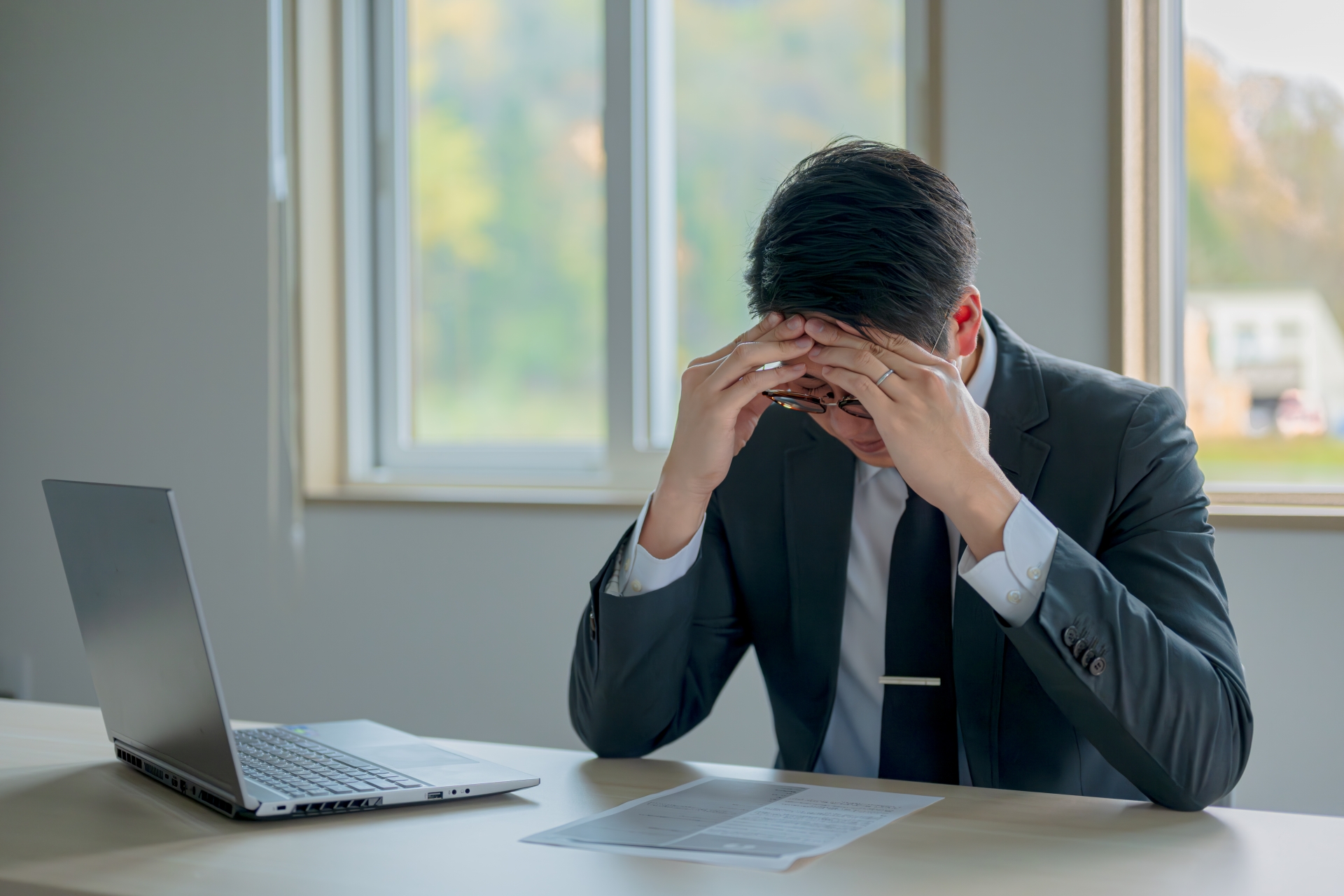職場で頭を押さえる男性