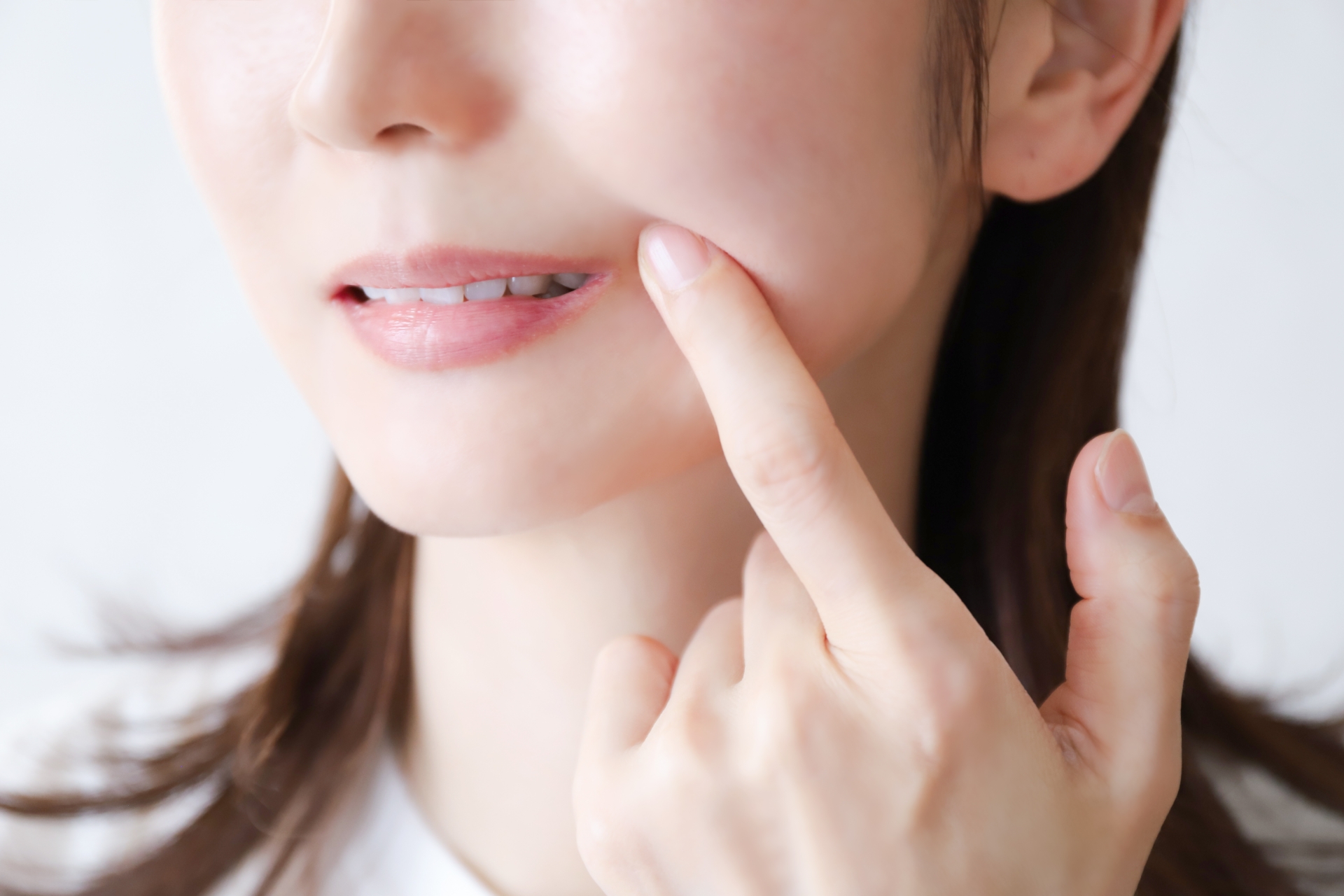 口元を指で押さえる女性