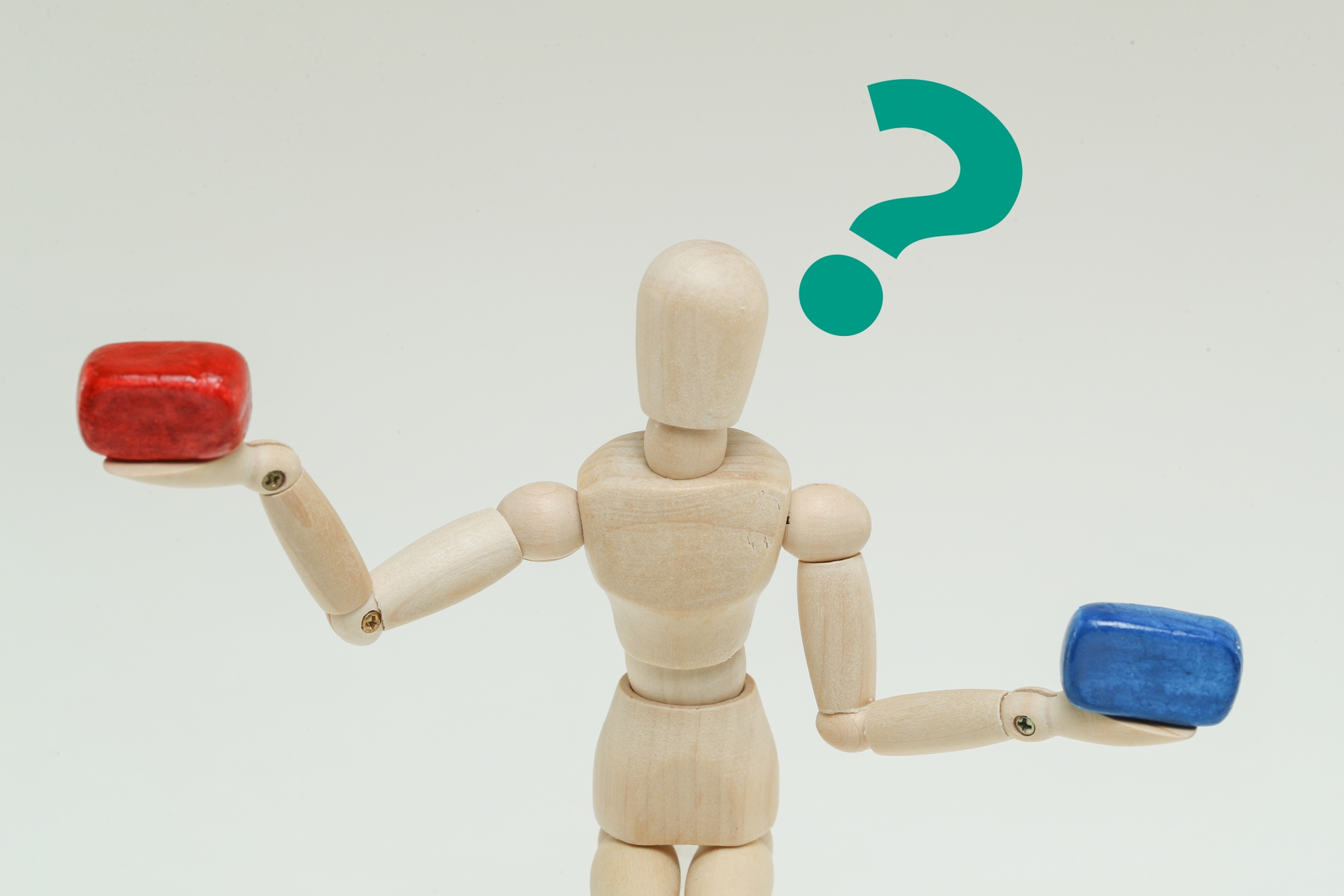 両手それぞれにブロックを持ち、重さを比較するデッサン人形