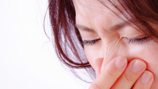 鼻を押さえる女性