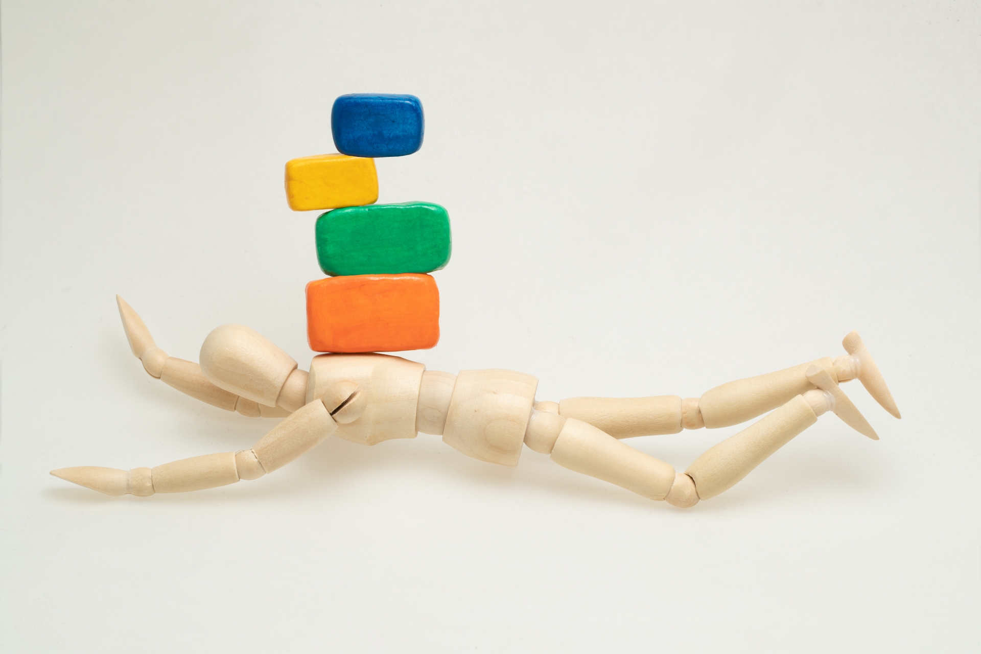 寝転がったデッサン人形の上にブロックが積まれている様子