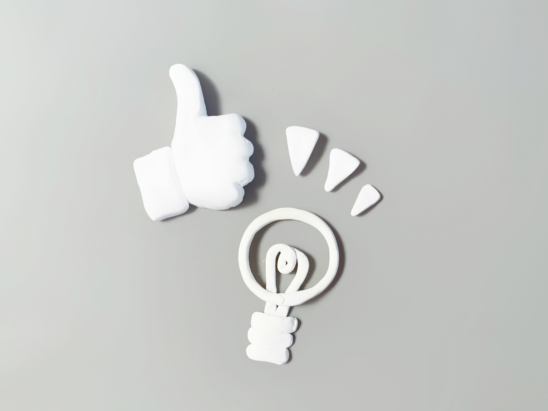 粘土で作った電球と親指を立てた手