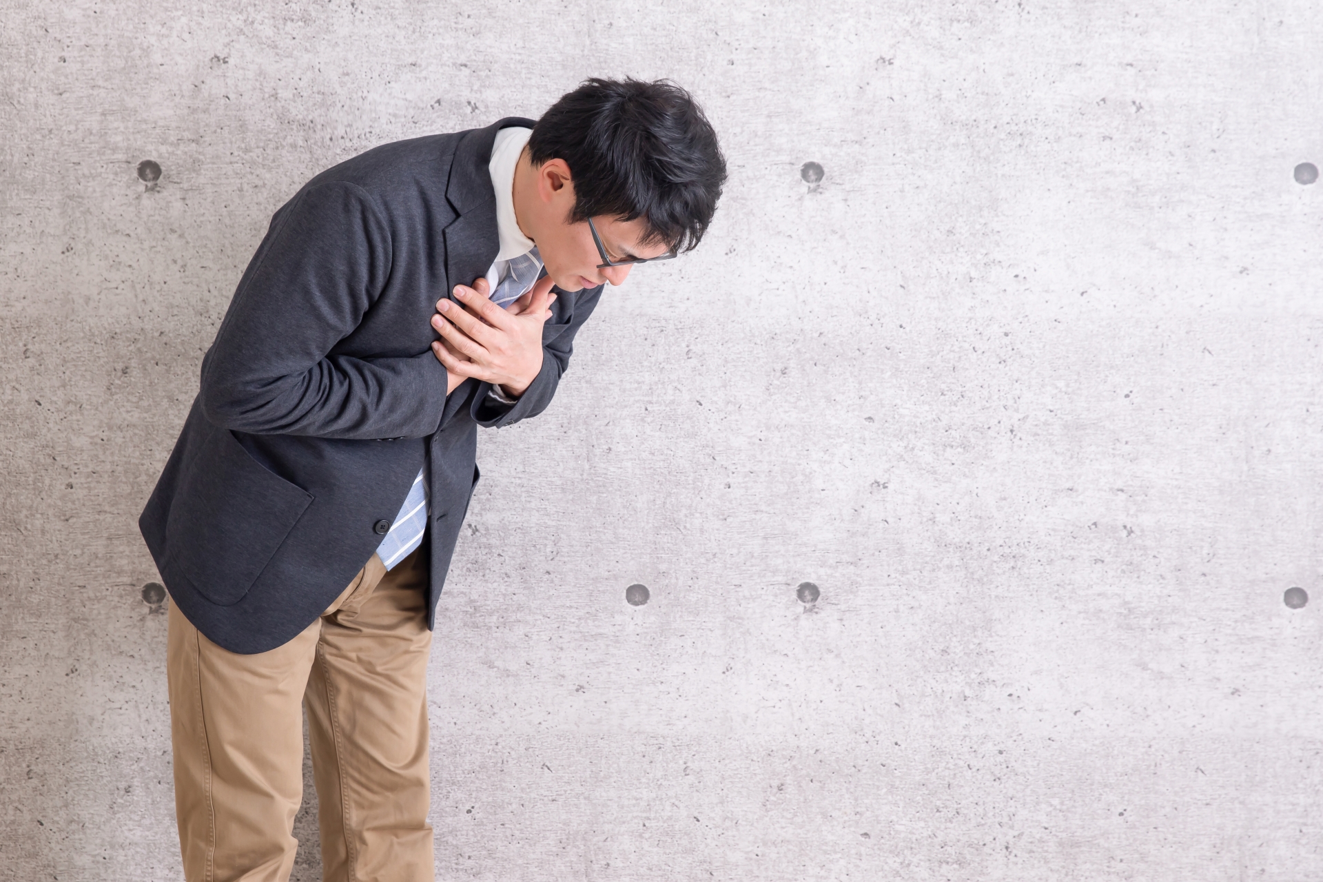胸を押さえて背を丸める男性