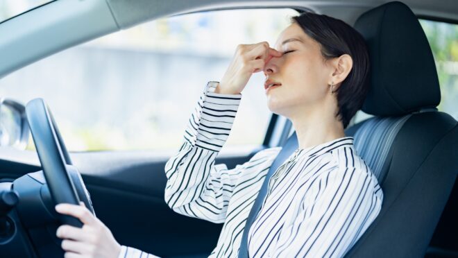 運転中に目頭をつまむ女性