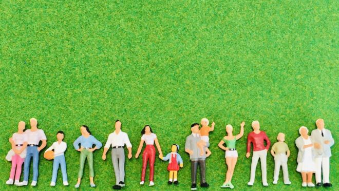 色々な年代の人間の人形が芝生の上に並んでいる様子