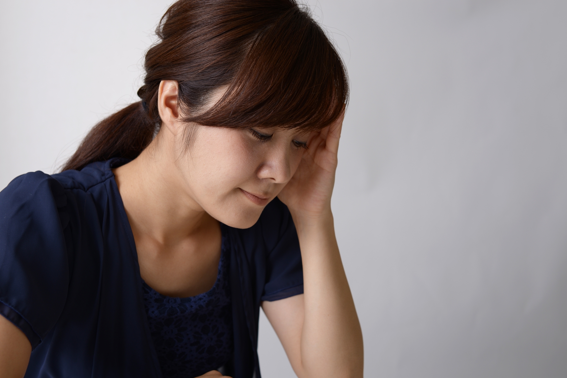 悩んで頭に手をやる女性