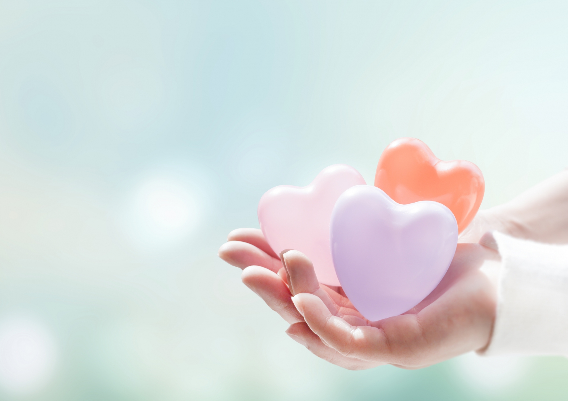 手にハートの形の風船が3個ある様子