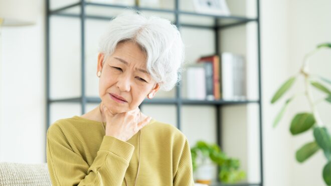 喉を押さえる高齢女性