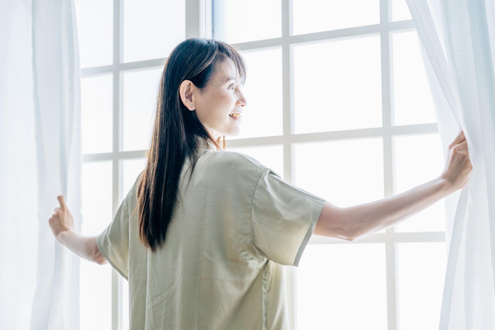 カーテンを開く女性