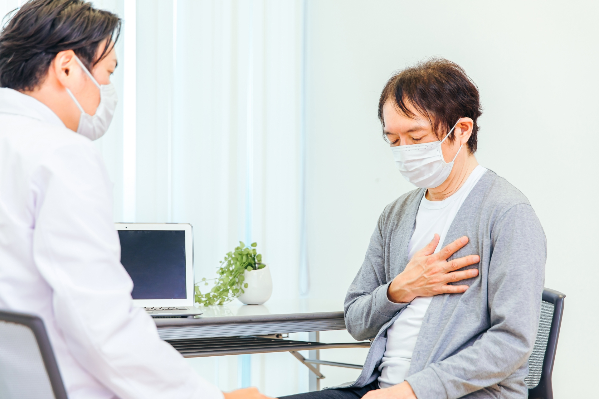 胸の痛みを医師に伝える男性