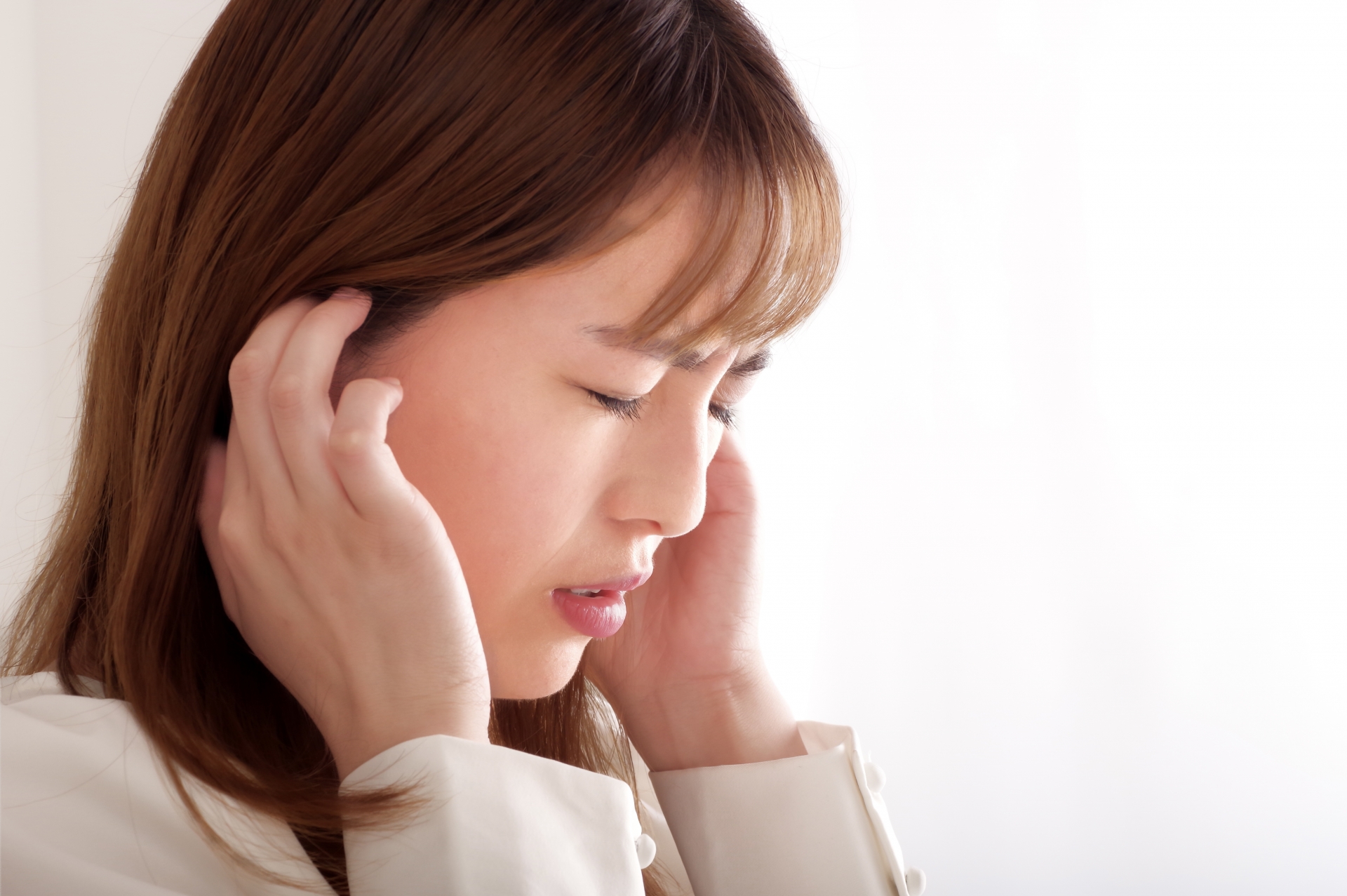 こめかみを押さえる女性