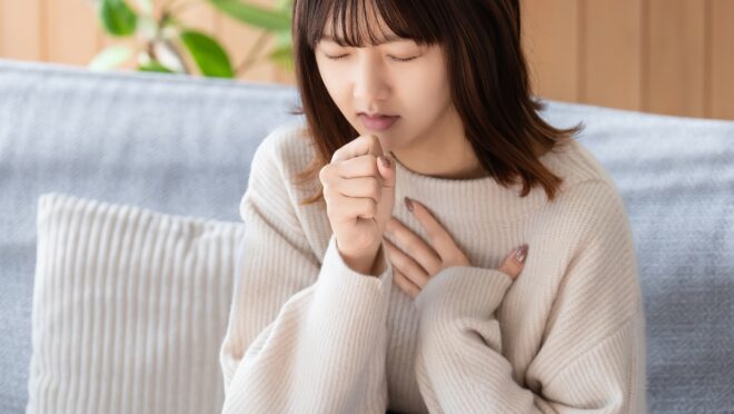 胸を押さえて咳をする女性